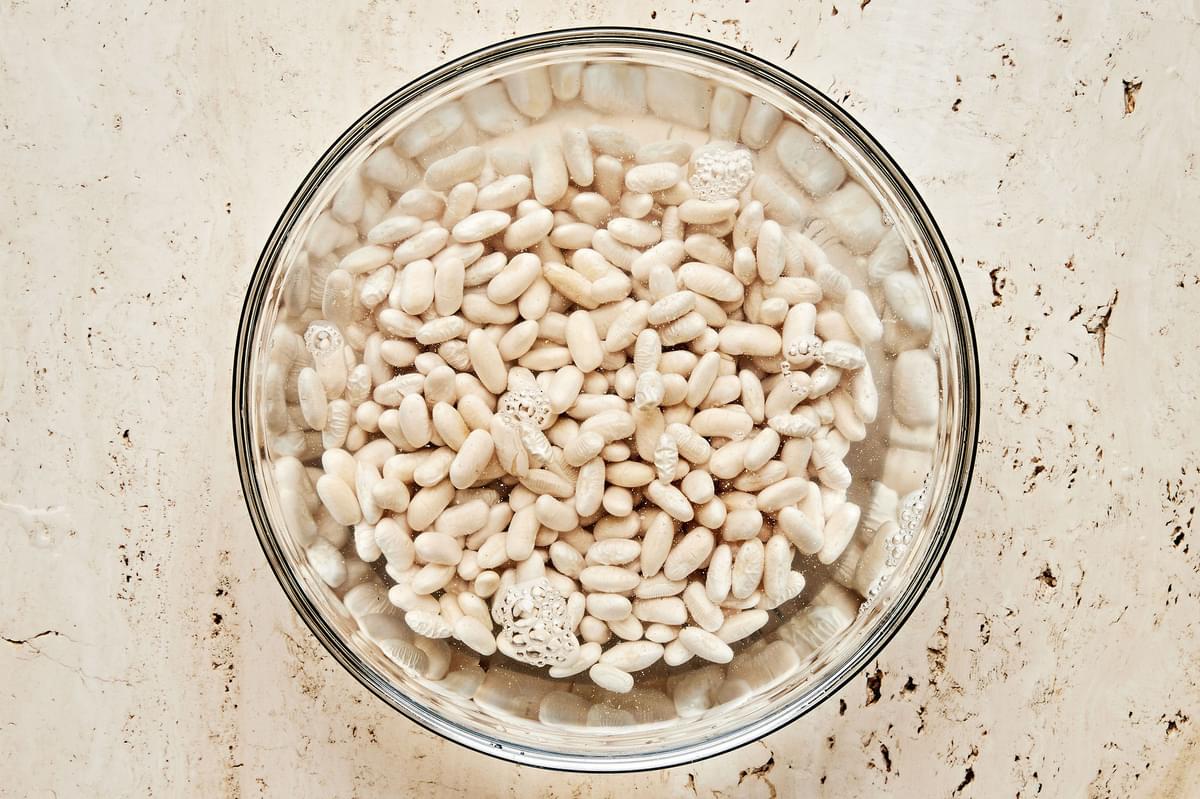 cannellini beans soaking in water in a large bowl