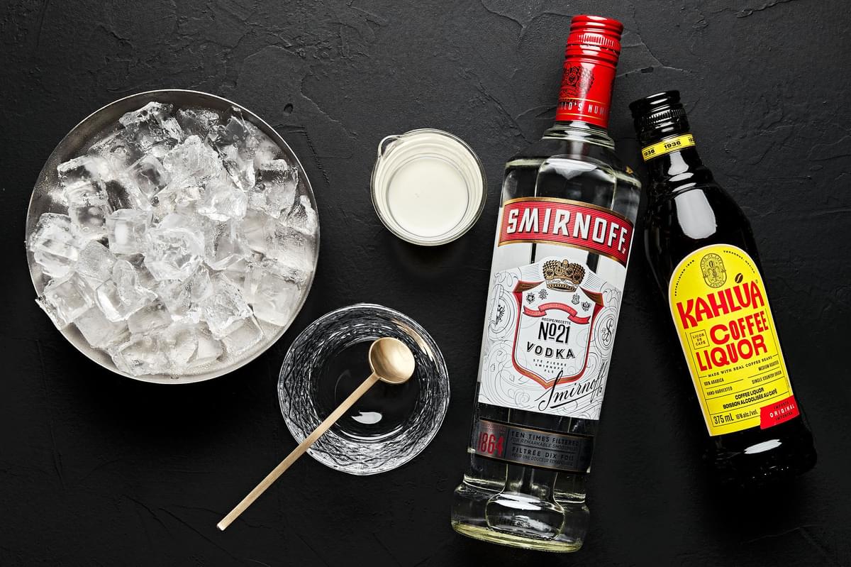 a bottle of vodka, a bottle of coffee liqueur, heavy cream, and ice to make a white Russian cocktail