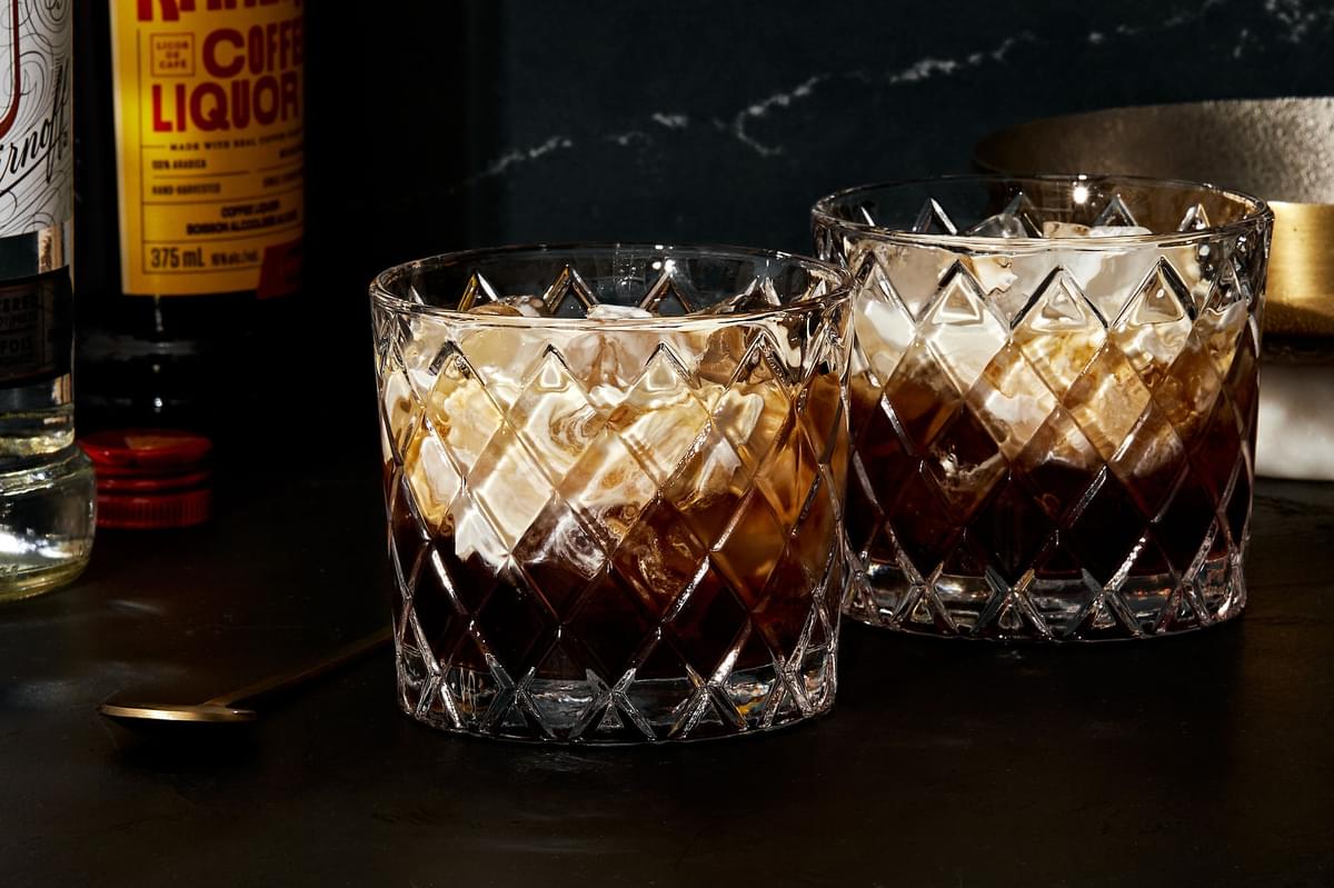 2 white russian cocktails over ice in cocktail glasses made with vodka, coffee liqueur, and heavy cream