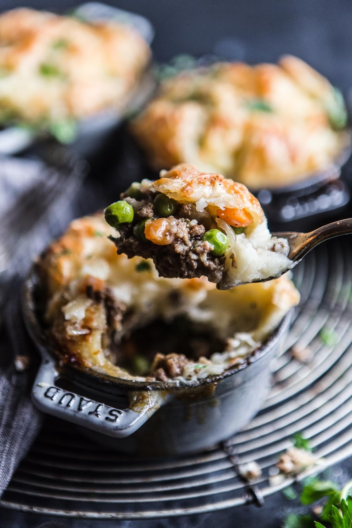 cocettes with llamb shepherd's pie with puff pastry and mashed potatoes sprinkled with gruyere cheese  with parsley on a fork