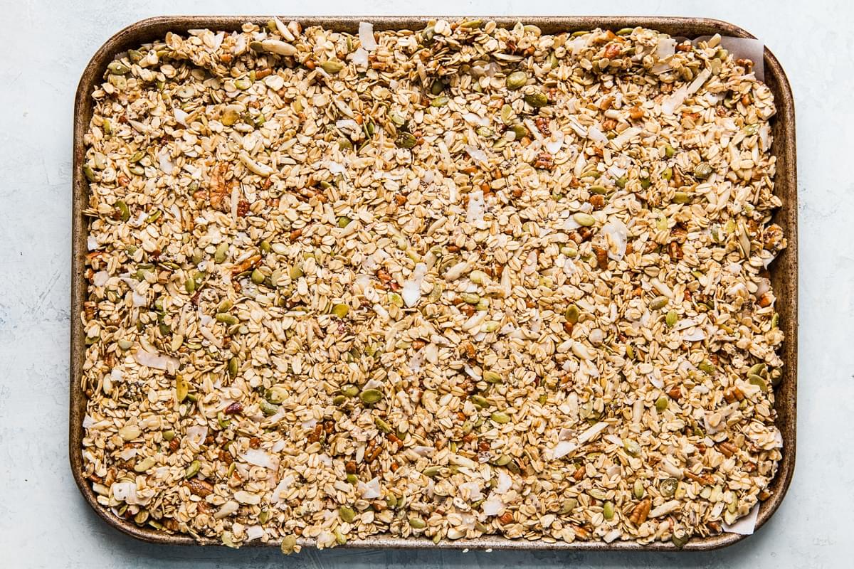 homemade granola on a baking sheet with oats, nuts and seeds and coconut