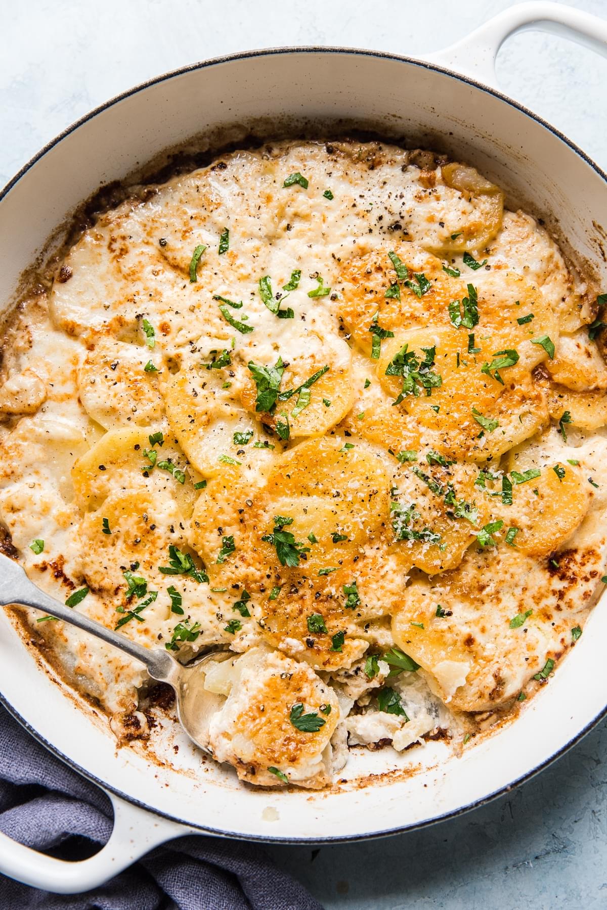 cheesy Potatoes au gratin in a baking dish with a soon