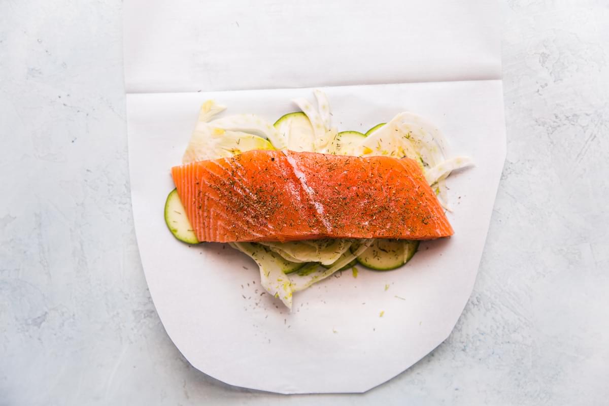 zucchini, fennel and salmon with dill, salt and pepper on parchment paper for en papillote