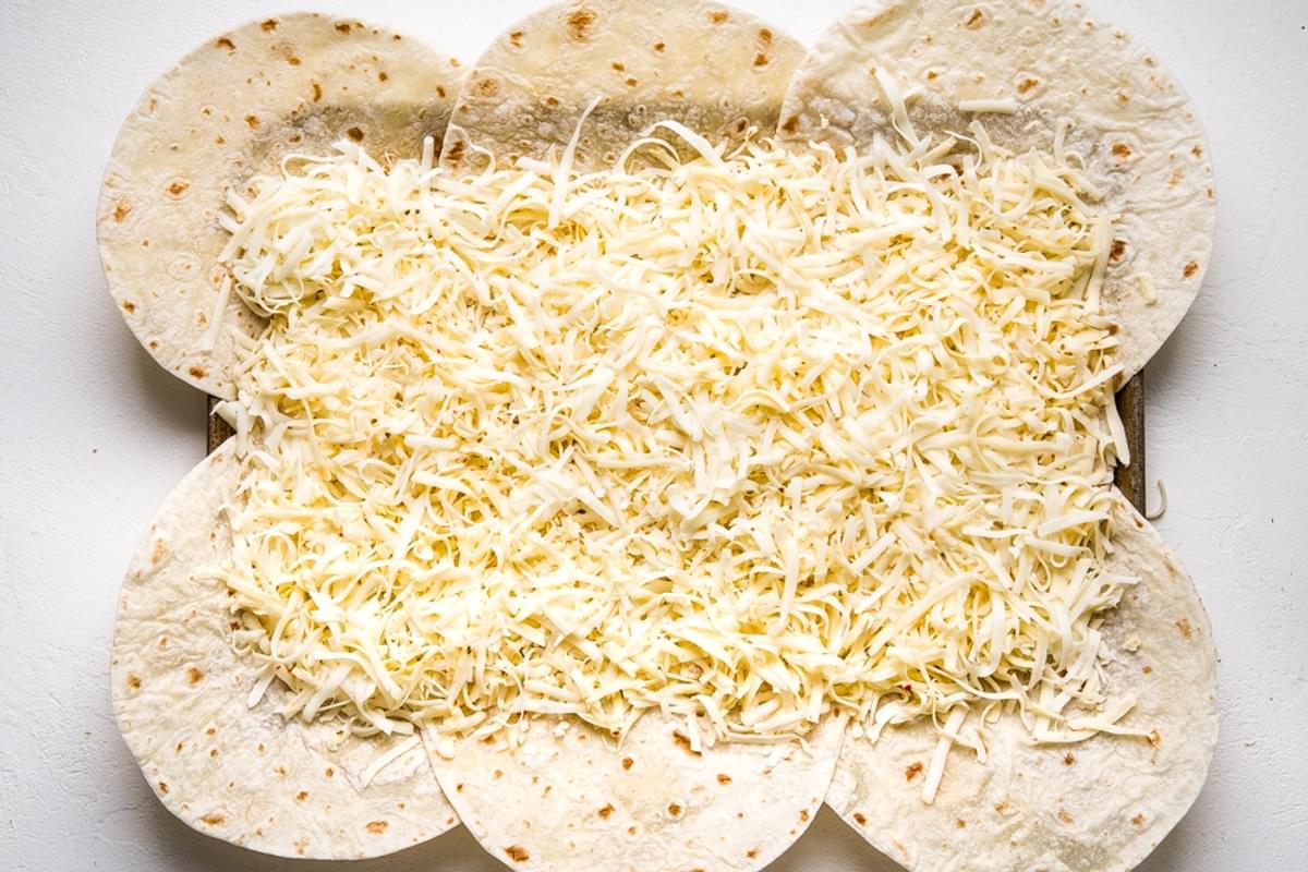 flour quesadillas on a baking sheet with shredded cheese