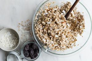 homemade Granola with Figs, Almonds and Coconut in a mixing bowl with a spoon