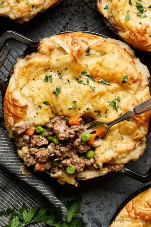 shepherds pies in small ramekins made with a puff pastry bottom, ground lamb and veggies topped with mashed potatoes