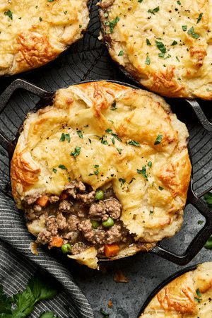 shepherds pies in small ramekins made with a puff pastry bottom, ground lamb and veggies topped with mashed potatoes