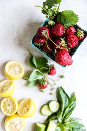 Basket of strawberries, lemons, cucumber and basil.