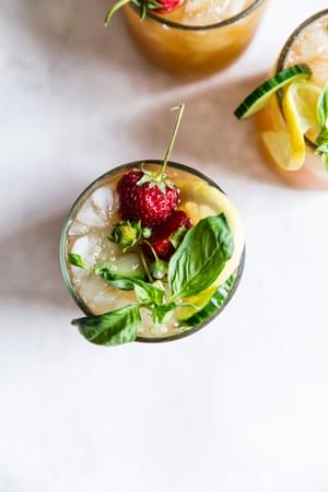 Close up of Pimm's Cup cocktails with strawberries, cucumber, lemon and basil.