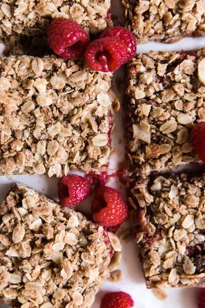 Raspberry Oat Bars cut into squares with a few fresh raspberries