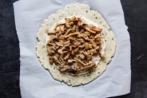 mushroom and onion filling on a raw galette dough placed on parchment paper