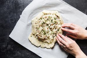 hands folding the edges of a mushroom galette