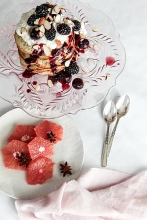 almond poppy seed pancakes on a pink cake plate next to a grapefruit salad