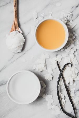 a bowl of coconut cream, a bowl of Malibu rum, a bowl of pineapple juice next to coconut shreds and a vanilla bean
