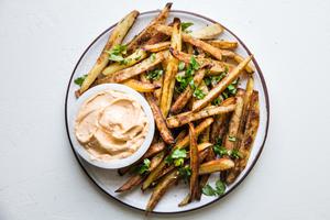 baked French fries on a plate with cilantro and chipotle aioli
