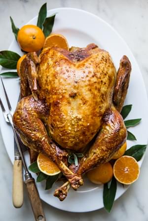 best roast turkey recipe with oranges and sage butter on a serving platter with sage leaves