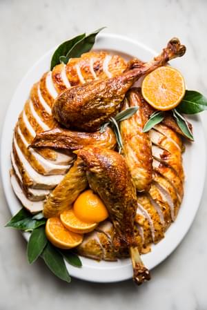 best roast turkey recipe with oranges and sage butter on a serving platter with sage leaves