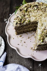 Yogurt and olive oil pistachio cake with lemon buttercream on a pink cake stand