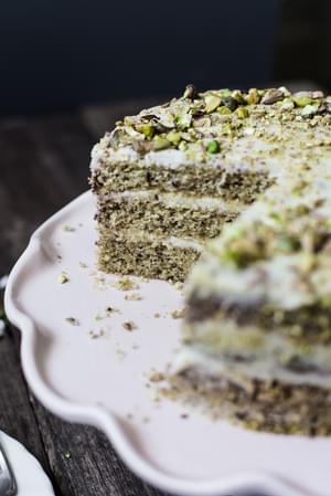 Yogurt and Olive Oil Pistachio Cake With Lemon Buttercream with a slice taken out