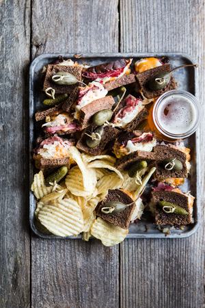Rueben sliders on a baking sheet made with rye bread, Russian dressing, sauerkraut and provolone topped with pickles