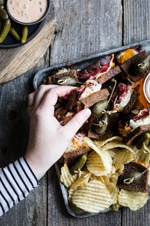 Rueben sliders on a baking sheet made with rye bread, Russian dressing, sauerkraut and provolone topped with pickles