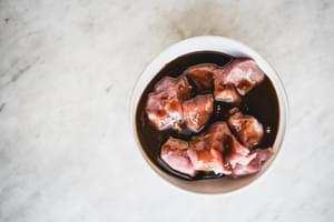 a bowl of pork tenderloin pieces marinating in hoisin sauce