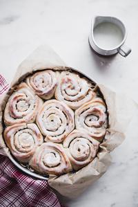 Cardamom Rolls with Almond Glaze in a baking dish with extra glaze on the size