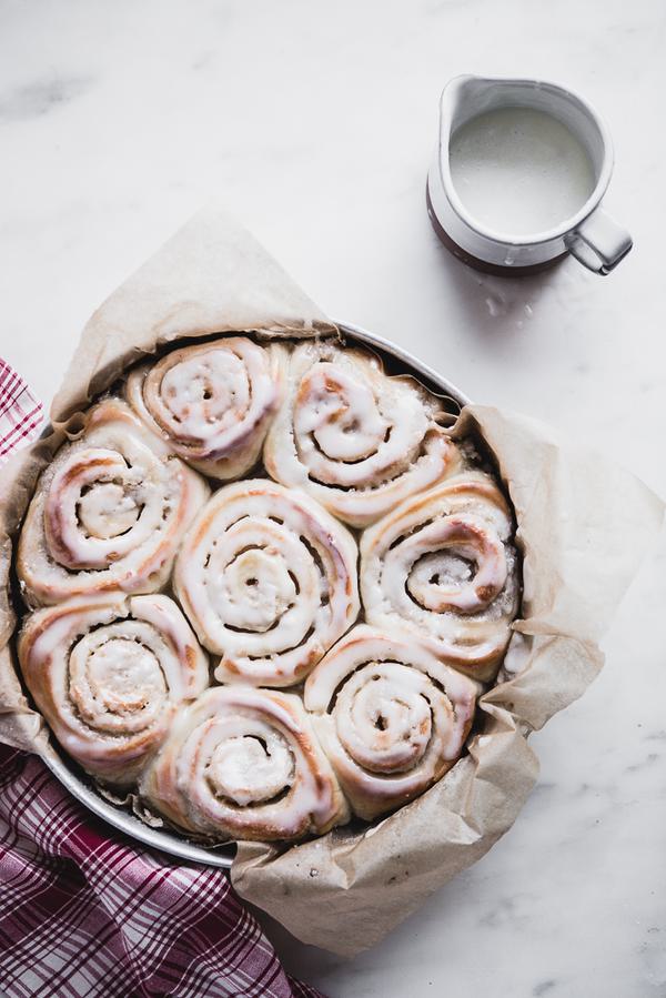 Cardamom Rolls with Almond Glaze in a baking dish with extra glaze on the size