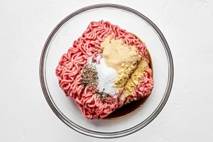 ingredients for burger patties in a bowl: Beef, garlic powder, Worcestershire, mustard powder, salt, and pepper