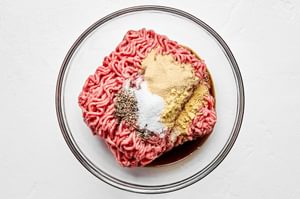 ingredients for burger patties in a bowl: Beef, garlic powder, Worcestershire, mustard powder, salt, and pepper