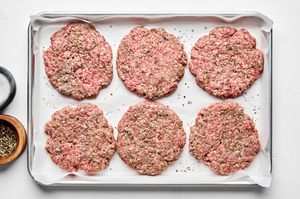 raw burger patties on a parchment lined baking sheet ready for cooking
