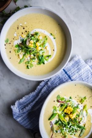 a soup pot full of Corn and Leek Bisque with 2 bowls and bread