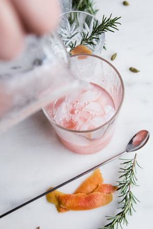 rosemary simple syrup being poured into Grapefruit Cardamom Gin Fizz