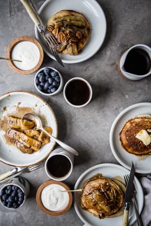 breakfast spread of blueberries, yogurt, coffee and Pancakes with Caramelized Bananas and Toasted Pecans