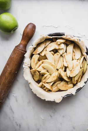 apple pie in the making next to a rolling pin