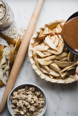caramel sauce being poured over an apple pie