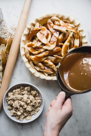 caramel sauce being poured over an apple pie