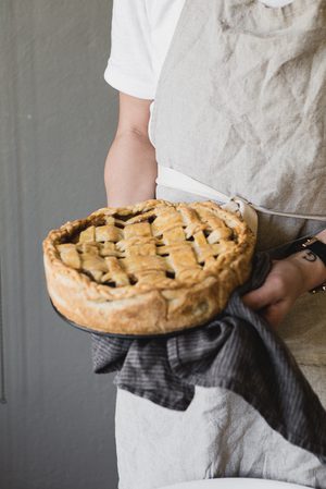 a person holding and apple pie with a linen