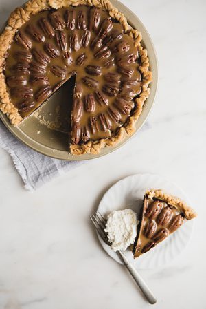 chocolate pecan pie with a slice taken out served on a plate with whipped cream and a fork