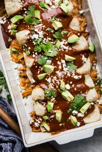 simple chicken mole enchiladas in a baking dish with avocado