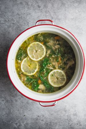 A large soup pot filled with white bean chicken soup garnished with fresh dill lemon slices