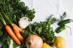 2 lemons, onion, carrots, garlic, kale, fresh dill and 2 jalapeños laid out on a counter.