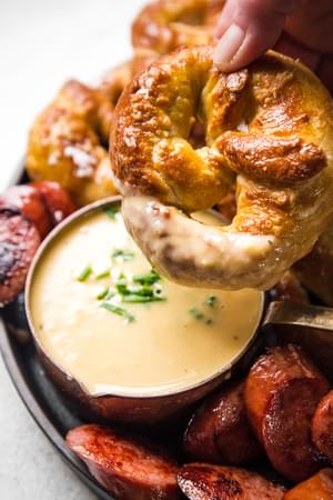 soft pretzel being dipped into white cheddar beer cheese