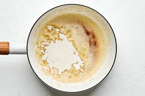 flour being stirred into a pan with melted butter