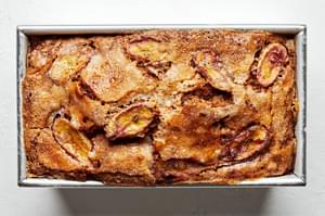 homemade banana bread topped with thinly sliced bananas and sprinkled with sugar in a loaf pan just out of the oven
