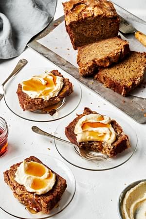 slices of the best homemade banana bread on plates slathered with maple mascarpone and a drizzle of extra maple syrup