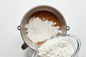 flour, baking soda and salt being poured into the butter, brown sugar and egg mixture for banana bread