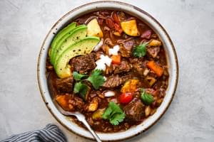 a bowl of homemade crockpot paleo chili in a bowl topped with avocado and cilantro