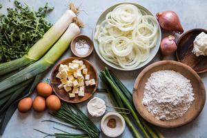 onions, shallots, chives, leeks, green onions, flour, butter, creme fraiche, arugula and eggs on a counter