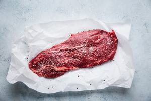 skirt steak on a piece of parchment paper with salt and pepper